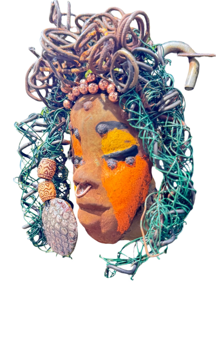Adda's unique design against a mossy tree bark backdrop is sure to catch your eye. This 3” x 5” 6oz. mixed media raku fire mask, crafted with 15 feet of 24 and 16 gauge wire, adds a touch of elegance to your HerDew mask collection. With a copper nose ring, three-colored complexion, and a large Raku fired earring with two wooden beads, Adda is a must-have for any mask enthusiast.