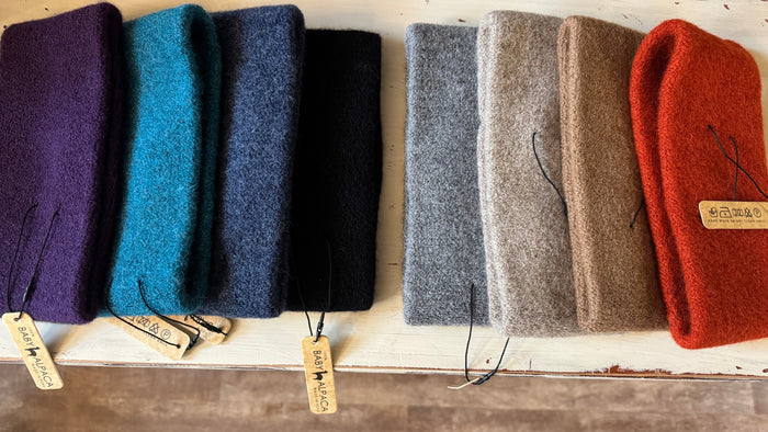 Row of colorful folded cloths on a wooden surface with tags.