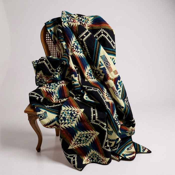 Colorful patterned blanket draped over a wooden chair on a plain background