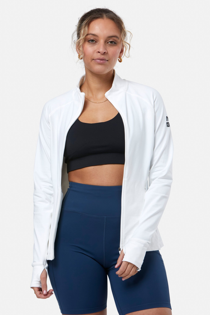 Woman wearing Gym+Coffee Relentless Full Zip Jacket in Ultra White by Gym+Coffee, shop the Gym+Coffee collection at Dotique