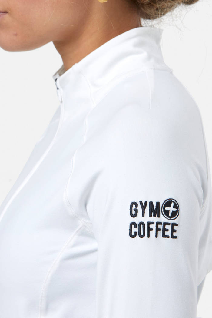 Close-up of the Gym+Coffee Relentless Full Zip Jacket in Ultra White worn by a model, shop Gym+Coffee at Dotique.