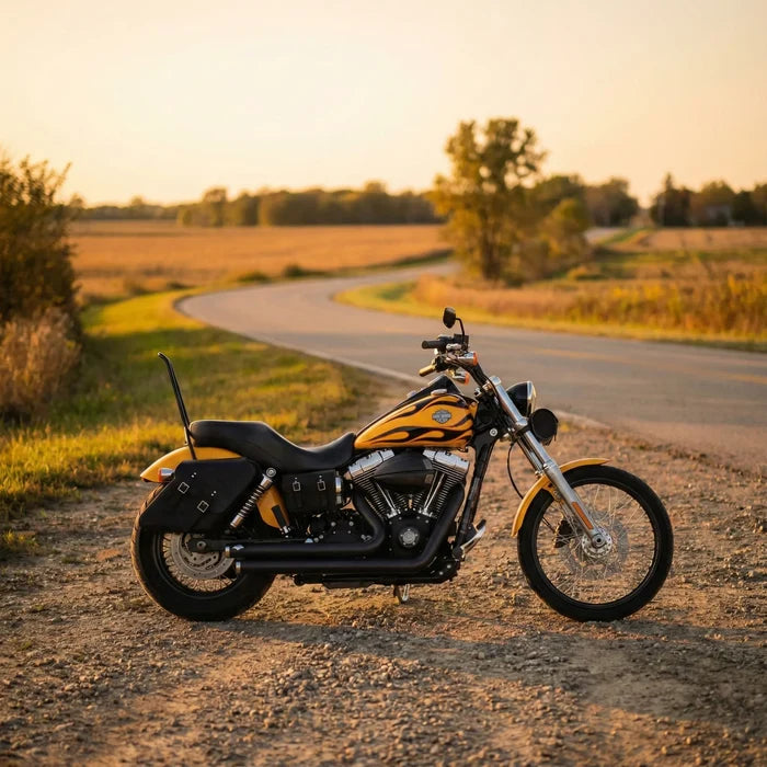 Motorcycle parked on a dirt road with a scenic background of fields and trees.