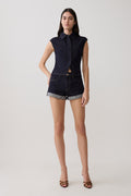 Woman wearing dark blue collared denim longline top with matching denim shorts.