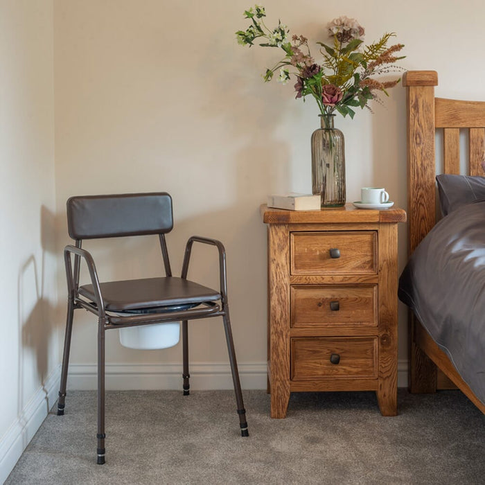 Demonstration of removing the commode pan or adjusting the height on NRS Dovedale Adjustable Commode with Detachable Arms.