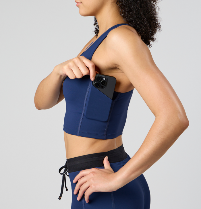 Side view of the Women's Race Crop in NY Navy, showcasing the underarm phone pocket, ergonomic scoop neckline, and versatile stretch Stamina™ fabric for ease of movement and support.