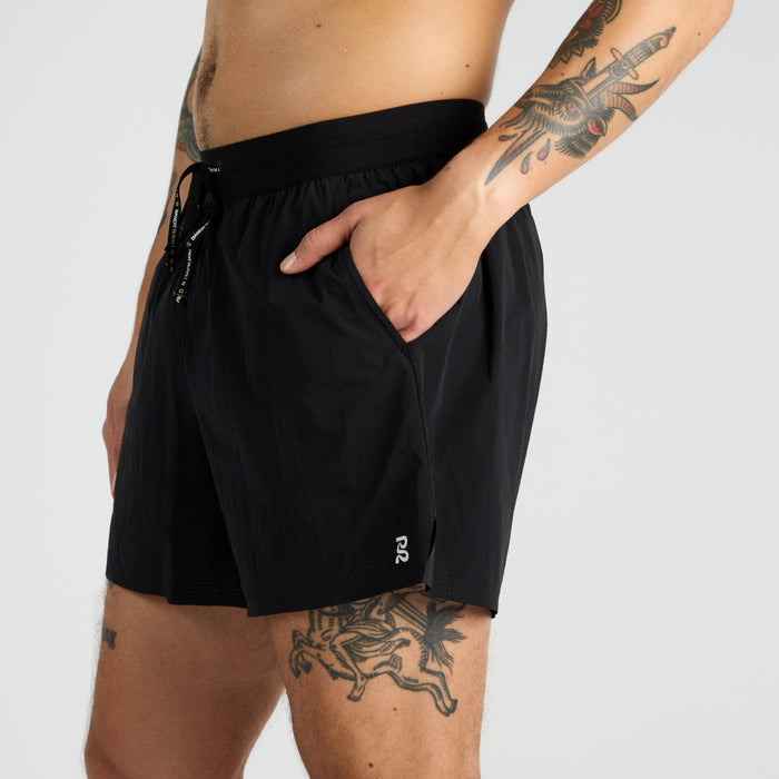 Side view of the Vento™ 5" Men's Training Short, featuring a reflective logo, custom waistband, and branded drawsting with a hand shown in one of the front slash pockets.